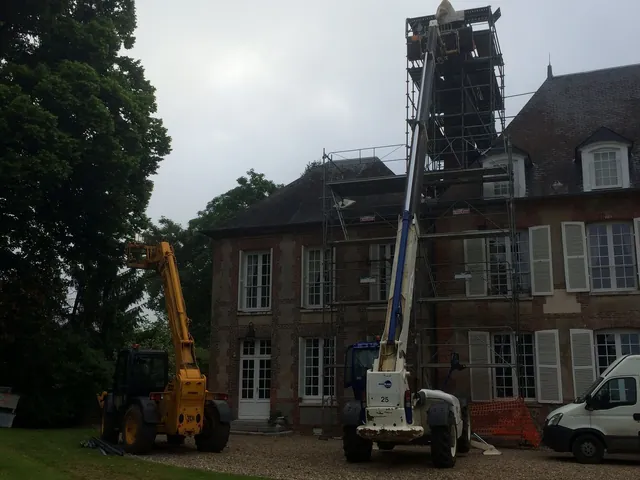 Maison de maître en brique et pierre sous échafaudage, deux chariots télescopiques au pied de la façade