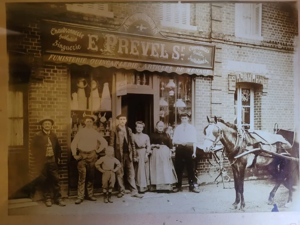 Photo ancienne de la famille Prevel devant sa boutique, sous l’enseigne peinte « E. Prevel, chaudronnerie, ferblanterie, zinguerie, couvertures »