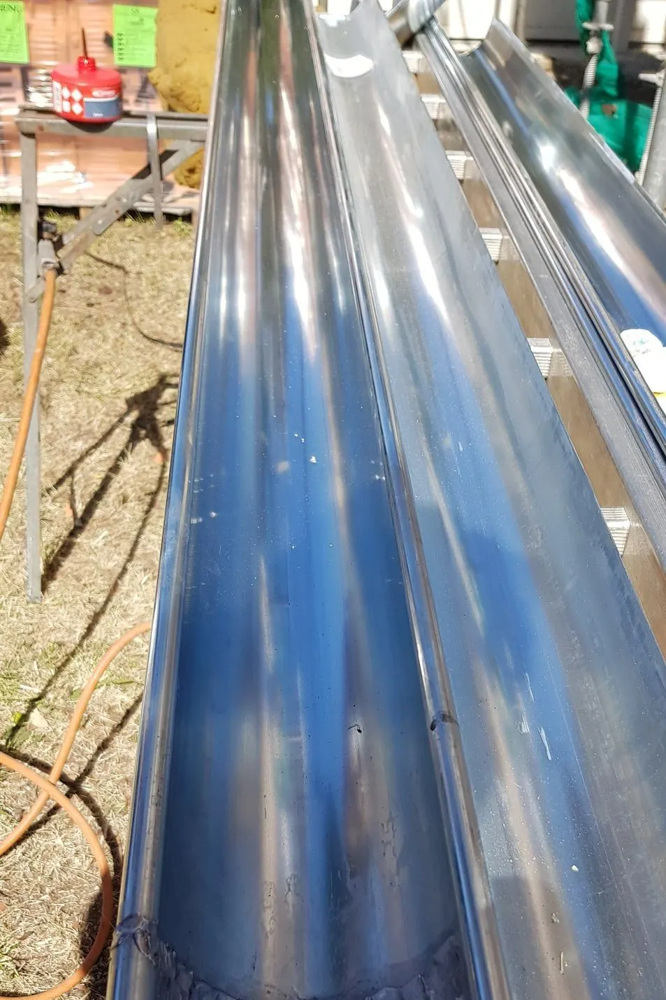 Gouttières en zinc neuves alignées dans un atelier de façonnage en plein air