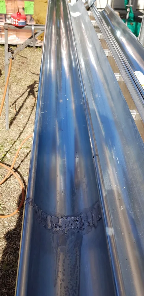 Gouttières en zinc neuves posées sur tréteaux, avec une soudure à l’étain visible au raccord