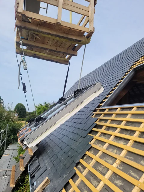 Fenêtre de toit en cours de pose sur une couverture en ardoise, liteaux et écran de sous-toiture apparents